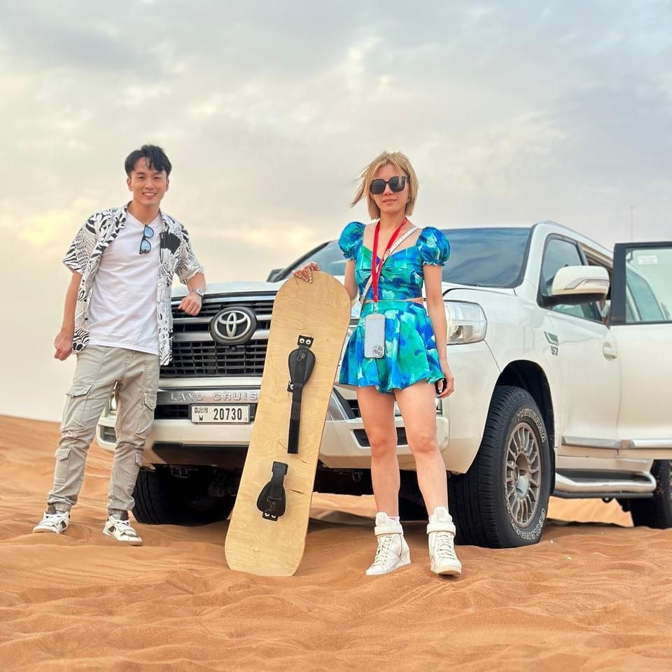 Couple posing with their Land Cruiser and sandboard in the Dubai desert