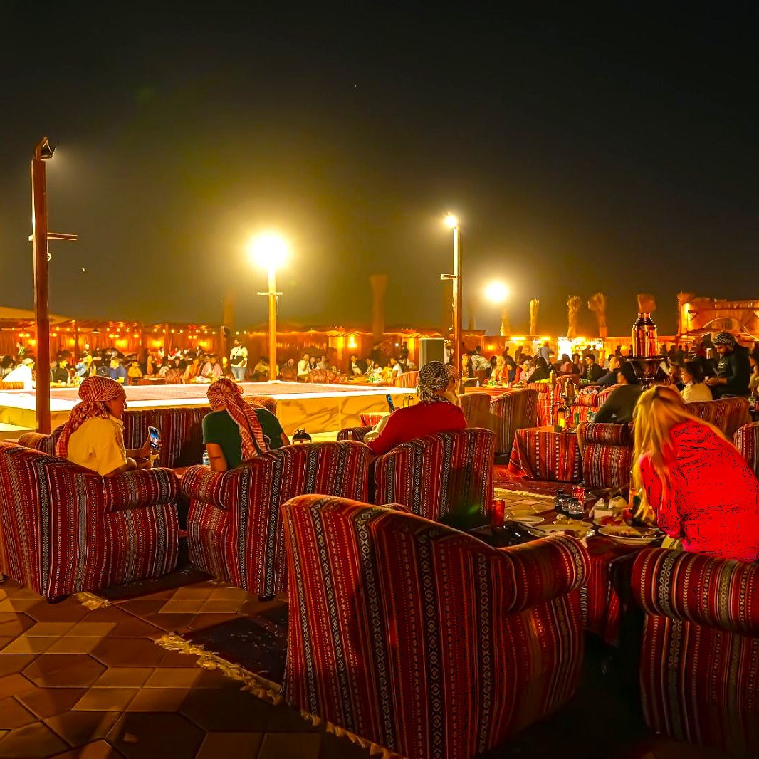 Guests relaxing at a desert safari camp under string lights at night
