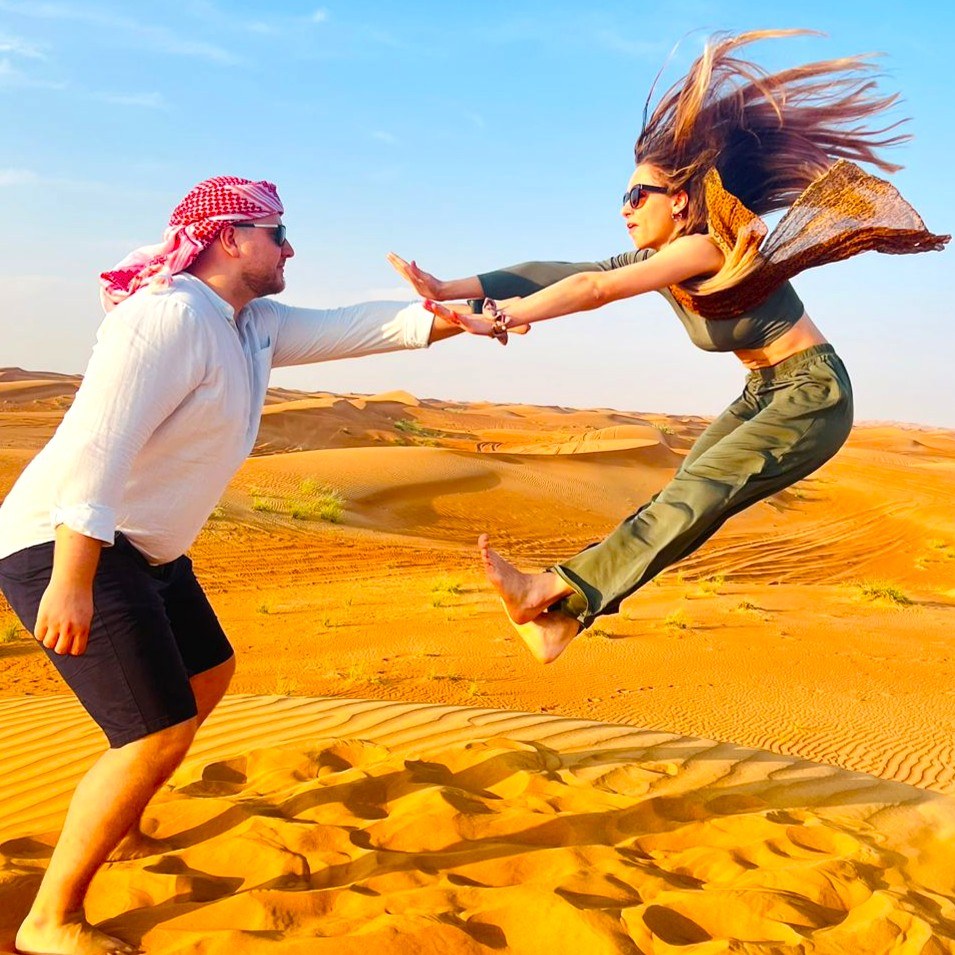 A playful moment between two guests on a Dubai desert dune