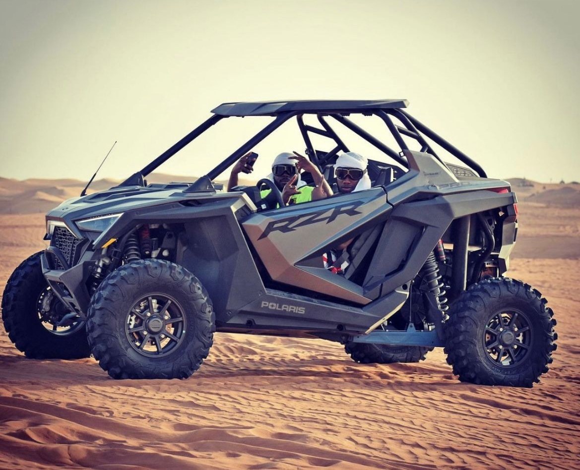Two friends riding a self-drive dune buggy in the Dubai desert