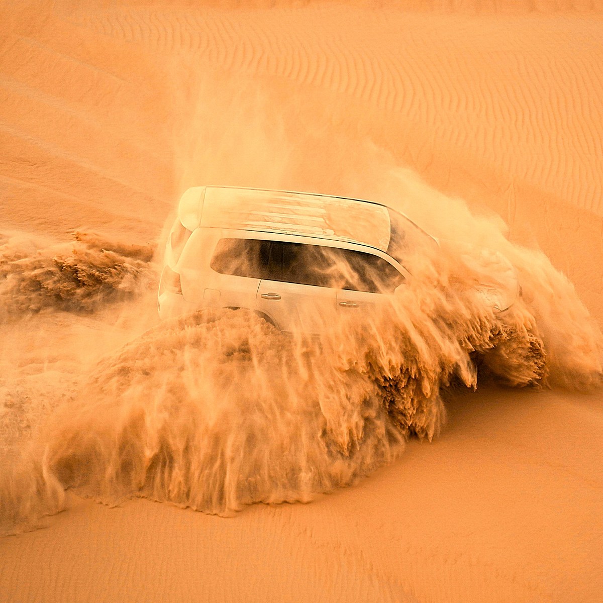 4x4 vehicle dune bashing in a cloud of sand during a Dubai desert safari