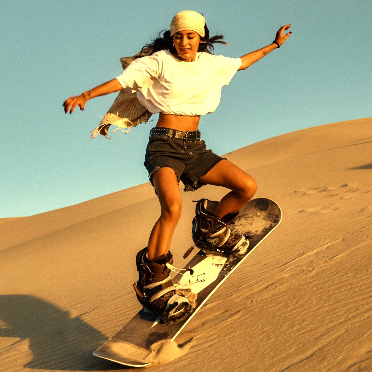 Guest sandboarding down a dune during a Dubai desert safari